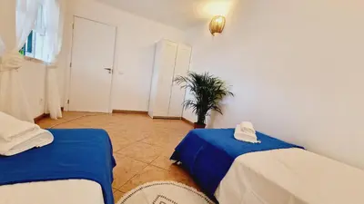 a room with two beds and a potted plant at Lazaro Beach House in Faro