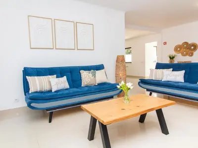 a living room with blue couches and a wooden table at Vila Paço no Vale by Stay ici Algarve Holiday Rental in Albufeira