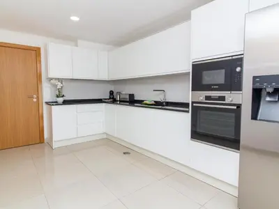 a white kitchen with black and white appliances at Vila Paço no Vale by Stay ici Algarve Holiday Rental in Albufeira