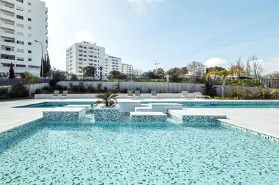 a swimming pool with blue water in a building at Modern 1-Bed Apartment with Terrace Albufeira in Albufeira