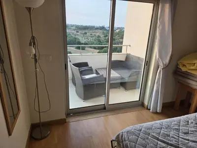 a bedroom with a balcony with a bed and a chair at Monte da Eira apt 62 in Albufeira