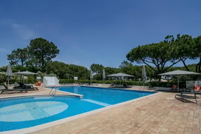 a large swimming pool with chairs and umbrellas at FLH Quinta do Lago Retreat with Terrace & Pool in Almancil