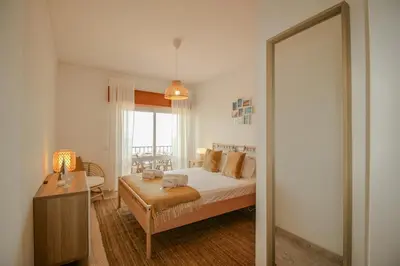 a bedroom with a bed and a table and a mirror at FLH Quarteira Seaview in Quarteira