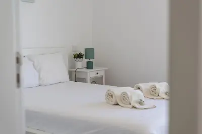 a white bedroom with a white bed with towels on it at Garret - Faro Apartment by HD in Faro