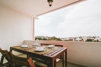 a wooden table with chairs and a large window at FLH Albufeira Boho Chic with Balcony in Albufeira