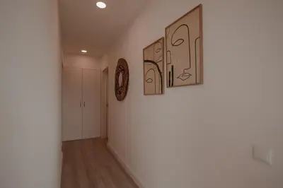 a hallway with three pictures on the wall and a clock at FLH Albufeira Boho Chic with Balcony in Albufeira