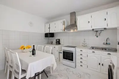 a kitchen with a white table and a white refrigerator at Casa Flôr in Albufeira