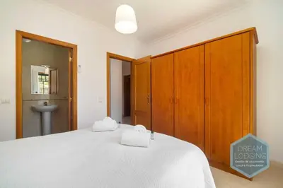 a bedroom with a large white bed with wooden cabinets at O Mar - Dream Lodging in Olhos de Água
