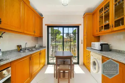 a kitchen with wooden cabinets and a table in it at O Mar - Dream Lodging in Olhos de Água
