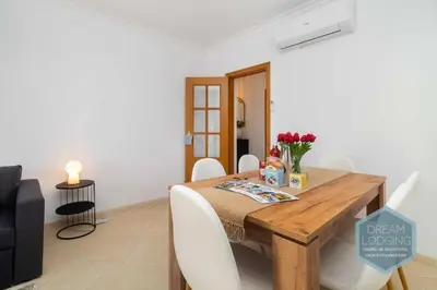 a dining room with a wooden table and white chairs at O Mar - Dream Lodging in Olhos de Água