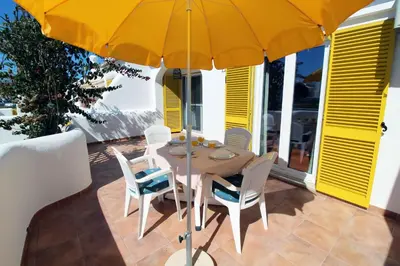a table and chairs under an umbrella on a patio at V2 - Aldeia do Golfe B2 in Quarteira