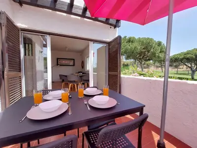 a black table with chairs and a pink umbrella at V2 - Bungalow 12 in Quarteira