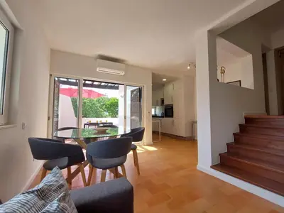 a living room with a table and chairs and a staircase at V2 - Bungalow 12 in Quarteira
