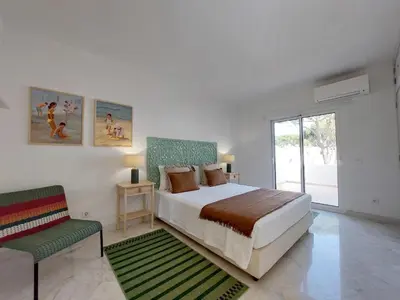a bedroom with a bed and a chair and a window at Vilamouratenis Duck by SAPvillas in Vilamoura