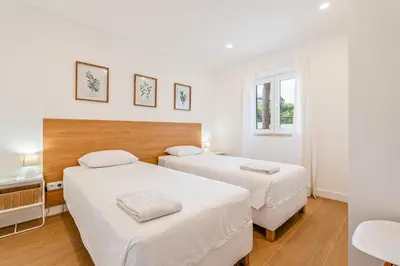 two beds in a room with white walls and wooden floors at Terra Alba in Olhos de Água