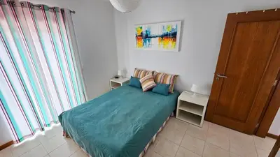 a bedroom with a bed with blue sheets and a door at T1 in Albufeira near Alfamar Hotel in Albufeira