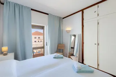 a bedroom with a white bed and a large window at Beachtime - Oura Beach Apartment in Albufeira