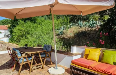 a table and chairs under an umbrella on a patio at Casa da Tita in Salir