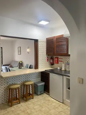 a kitchen with two stools and a room with a bed at Apartamento em São Rafael in Albufeira
