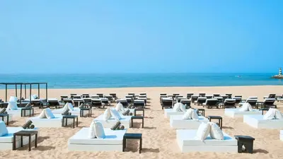 a beach with white lounge chairs and the ocean at Beach Apartment Marina Vilamoura in Vilamoura