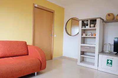 a living room with a red couch and a mirror at Bloom Place VALE DO LOBO - Apartamento acolhedor com terraço in Vale do Lobo