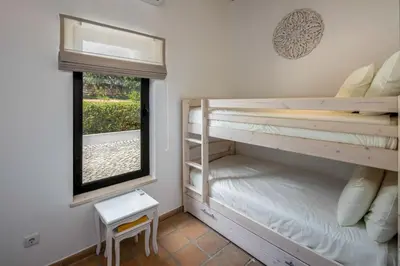 a bedroom with two bunk beds and a window at Villa Zambujal in Boliqueime