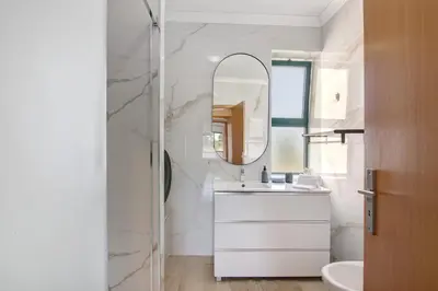 a white bathroom with a sink and a mirror at Salgados Beach House in Albufeira