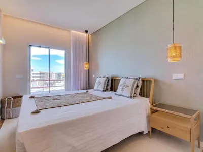 a bedroom with a large bed and a window at Penthouse T4 com Vista Mar em Quarteira in Quarteira