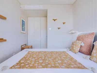 a bedroom with a white bed with a blanket on it at Penthouse T4 com Vista Mar em Quarteira in Quarteira