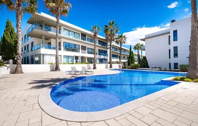 a swimming pool in front of a building with palm trees at Beach 1Min! & Pool - Private Parking, AC & WiFi in Quarteira