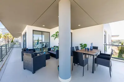 a dining room with a table and chairs on a balcony at Beach 1Min! & Pool - Private Parking, AC & WiFi in Quarteira