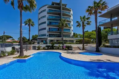 a swimming pool in front of a building at Beach 1Min! & Pool - Private Parking, AC & WiFi in Quarteira