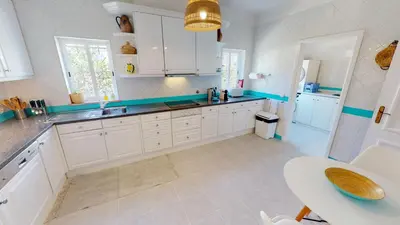 a kitchen with white cabinets and a sink and a table at Villa Sunset,sleeps 9,heatable pool,walk to marina in Vilamoura