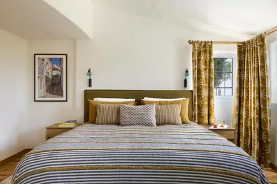 a bedroom with a large bed with a striped comforter at Casa Rosa dos Ventos in Guia