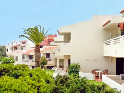 a view of a building with a palm tree at Aura Village - City Beach Apartments in Albufeira