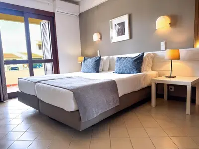 a bedroom with a large bed with blue pillows at Aura Village - City Beach Apartments in Albufeira