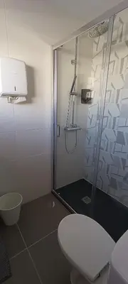 a bathroom with a glass shower with a toilet at Faro Station Eleven Guest House in Faro