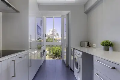 a laundry room with white cabinets and a window at CORCOVADA SUNSET Just 5 min from the Strip in Albufeira