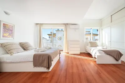 a white bedroom with a bed and a large window at Luxe Penthouse, BBQ, hot spa, games, ocean view - By Seareen in Albufeira