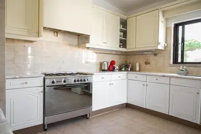 a kitchen with white cabinets and a stove top oven at Fernando Pessoa Villa in Faro