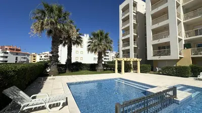 a swimming pool with two lawn chairs and palm trees at Wave by Check-in Portugal in Albufeira