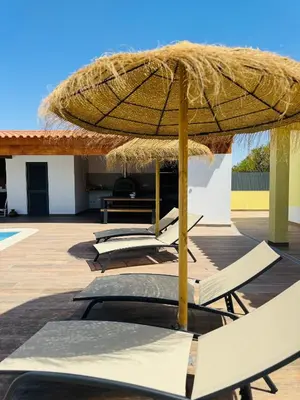 a row of lounge chairs under a straw umbrella at Villa 20age - Jacuzzi - Heated pool - Algarve in Albufeira