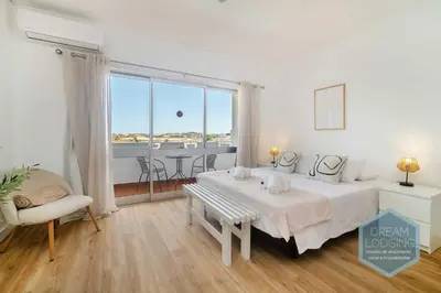 a bedroom with a bed and a table and a window at Alamos - Dream Lodging in Albufeira