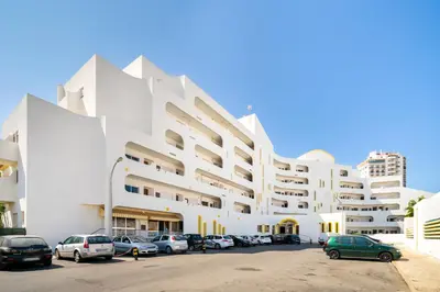 a white building with cars parked in a parking lot at Alamos - Dream Lodging in Albufeira