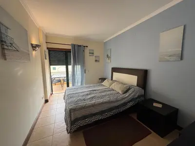 a bedroom with a bed and a door to a patio at T1 dos Salgados in Guia
