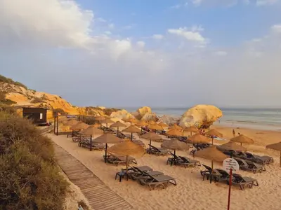 a beach with chairs and umbrellas and the ocean at T1 dos Salgados in Guia