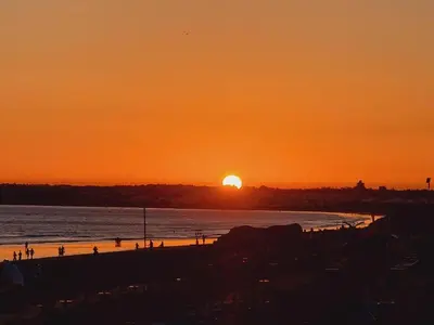 a sunset on a beach with the sun setting at T1 dos Salgados in Guia