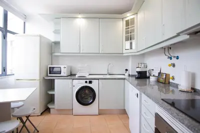a white kitchen with a washing machine in it at Modern 3-bedroom Retreat in Faro's City Center in Faro