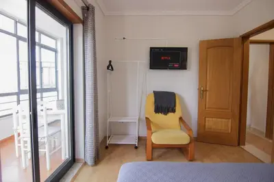 a bedroom with a yellow chair and a television on the wall at Modern 3-bedroom Retreat in Faro's City Center in Faro