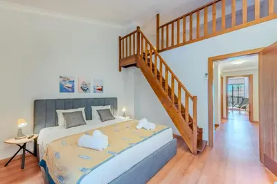 a bedroom with a large bed and a staircase at Sao Rafael TownHouse with Pool in Albufeira